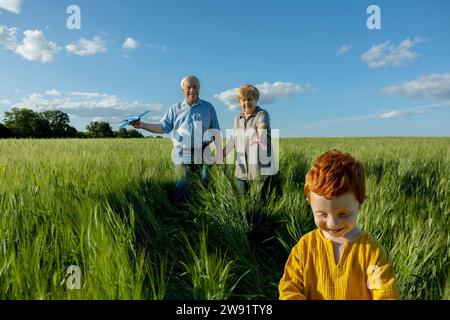 Senior couple spending leisure time with grandson in field Stock Photo