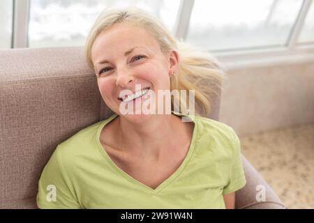 Happy woman relaxing on sofa at home Stock Photo