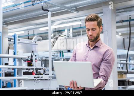 Young engineer working on laptop at factory Stock Photo