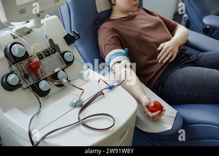 Young woman lying on couch with ball in hand at blood donation center Stock Photo