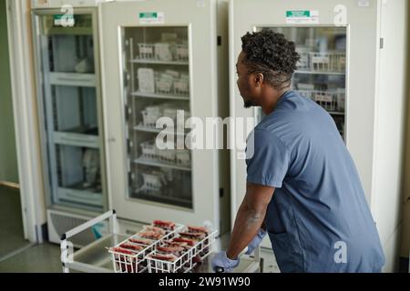 Lab technician pushing trolley of blood bags Stock Photo