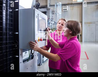 Technicians operating and examining machinery in factory Stock Photo