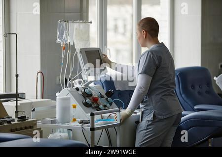 Young healthcare worker operating equipment at blood donation center Stock Photo