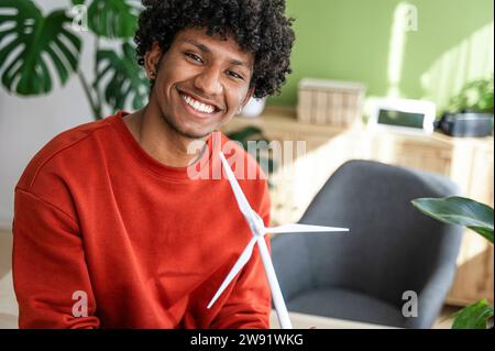Smiling engineer with wind turbine model at home office Stock Photo