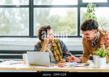 Happy young graphic designers at desk in office Stock Photo