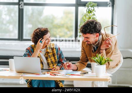 Young graphic designer discussing with colleague at office Stock Photo