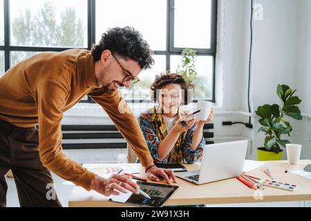 Happy graphic designers working together at desk in office Stock Photo
