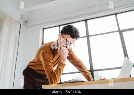 Focused graphic designer leaning on desk at office Stock Photo