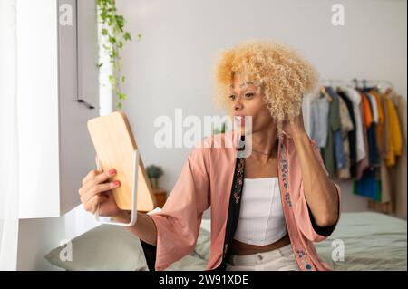 Transgender woman looking in mirror sitting at home Stock Photo