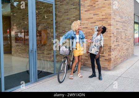 Transgender woman talking with happy friend standing near building Stock Photo