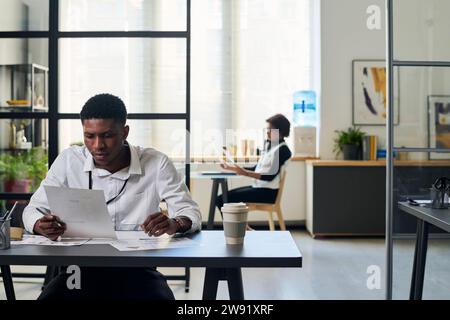 Young businessman reading documents at desk in office Stock Photo