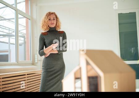Smiling architect holding eyeglasses and standing in office Stock Photo