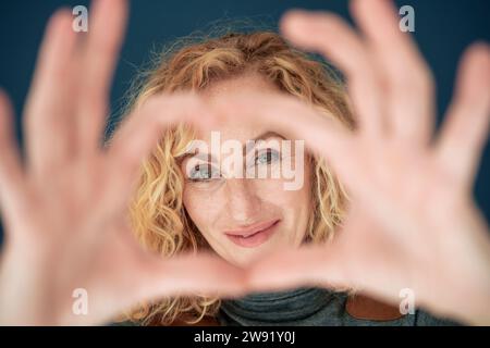 Smiling woman gesturing heart shape Stock Photo