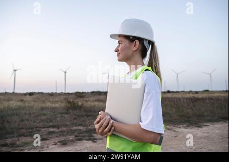 Thoughtful engineer holding laptop and standing at field Stock Photo