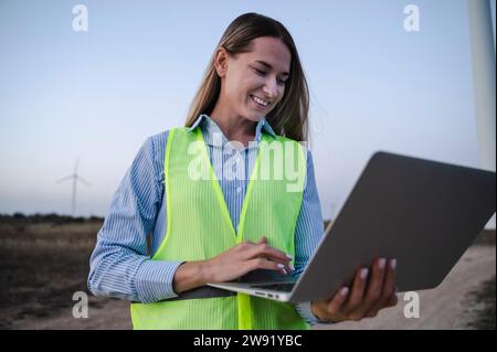 Happy engineer using laptop at field Stock Photo