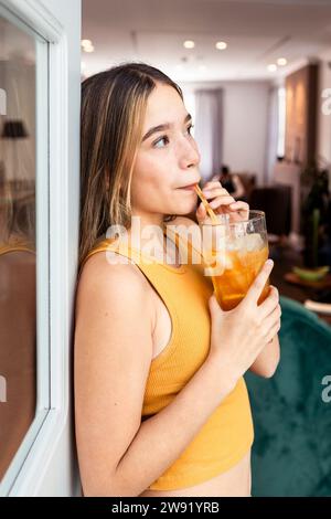 Woman sipping iced tea through straw at home Stock Photo