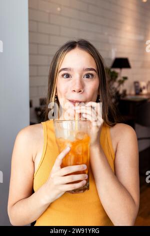 Young woman drinking iced tea with straw at home Stock Photo