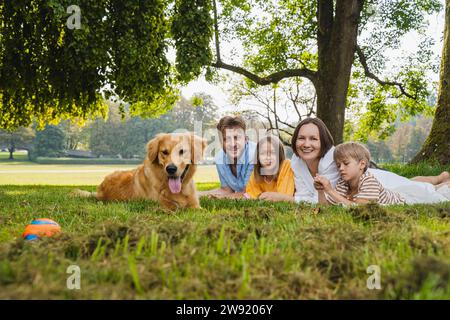 Happy family with dog lying on grass at park Stock Photo