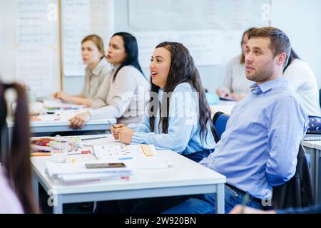 Multi-ethnic students sitting at desk studying together in classroom Stock Photo