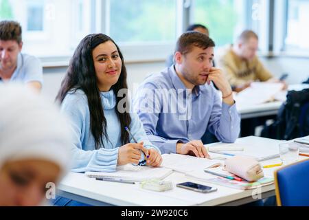 Smiling student sitting by friend at desk in classroom Stock Photo