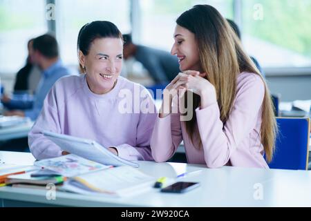 Smiling women discussing over book at desk in classroom Stock Photo
