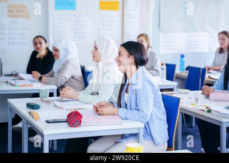 Multi-ethnic students sitting at desks learning together in classroom Stock Photo