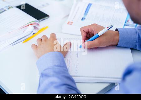 Student writing in notebook at desk in classroom Stock Photo