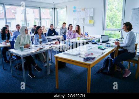 Smiling teacher teaching to multi-ethnic students in classroom Stock Photo