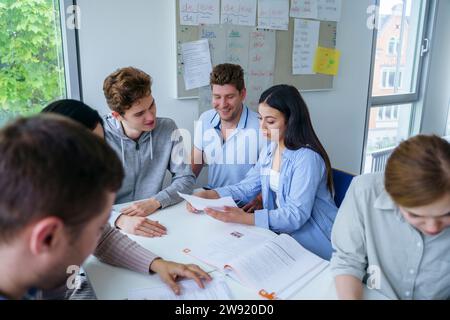 Multi-ethnic students discussing and studying at desk in classroom Stock Photo