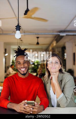Smiling multiracial business colleagues sitting at cafe Stock Photo