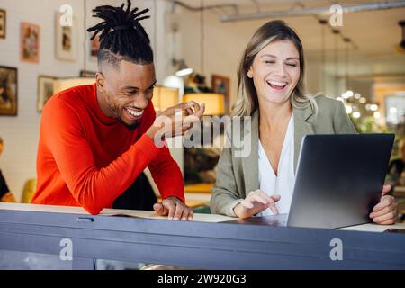 Happy business colleagues enjoying working on laptop at cafe Stock Photo