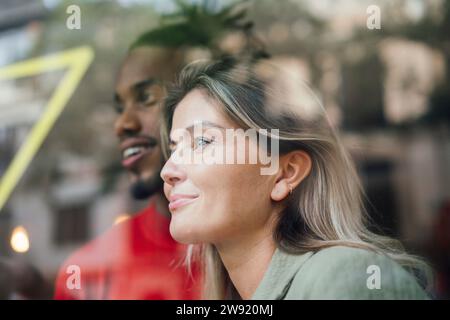 Smiling businesswoman looking through glass window Stock Photo