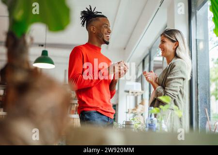 Happy young architects standing and discussing at cafe Stock Photo