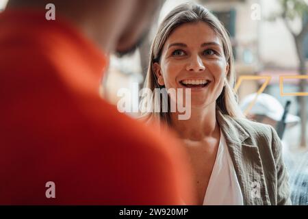 Young smiling businesswoman with coworker at cafe Stock Photo