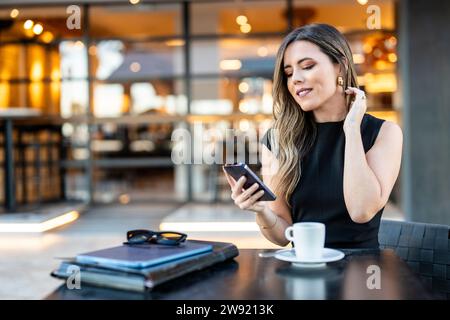 Businesswoman using smart phone at sidewalk cafe Stock Photo