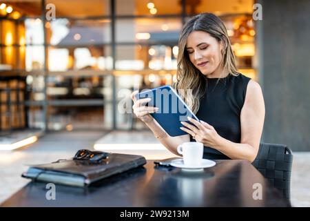 Businesswoman working on tablet PC at sidewalk cafe Stock Photo