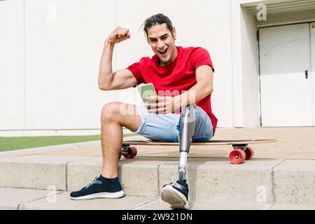 Cheerful man with disability flexing muscles and using mobile phone Stock Photo