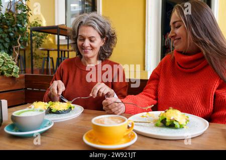 Smiling mother and daughter having breakfast together at cafe Stock Photo