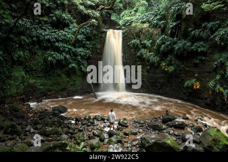 Young man standing in front of waterfall Stock Photo