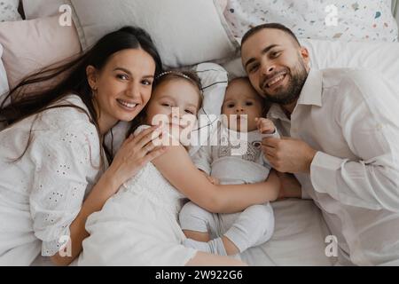 Smiling parents lying with children on bed at home Stock Photo