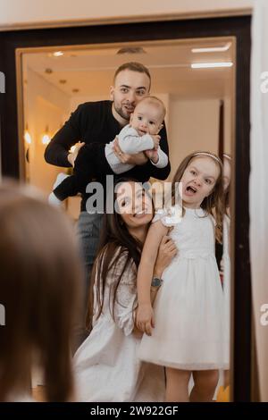 Playful parents with son and daughter making face in mirror Stock Photo