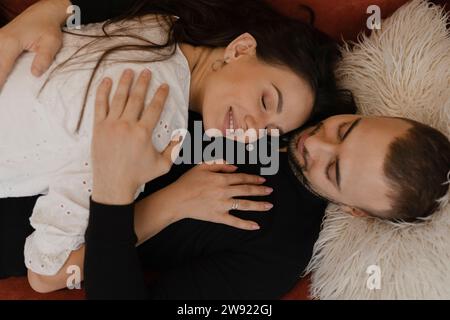 Loving couple lying down and embracing at home Stock Photo