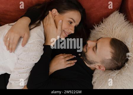 Young man lying down and embracing woman at home Stock Photo