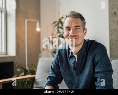 Smiling mature man sitting in living room Stock Photo