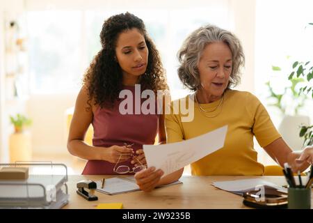 Businesswomen examining and having discussion over documents at desk in office Stock Photo