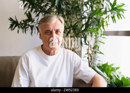 Confident senior man sitting on sofa at home Stock Photo