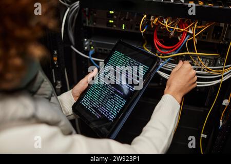 Engineer working on tablet PC with computer codes and setting up database Stock Photo