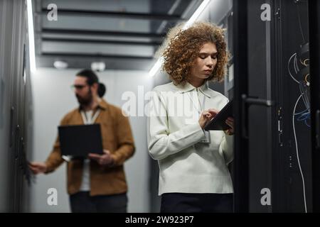 IT engineer using tablet PC with colleague working in background Stock Photo