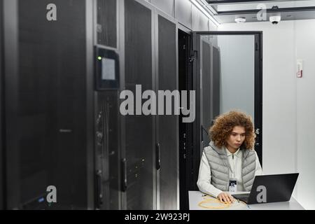 Engineer working on laptop and sitting in server room Stock Photo