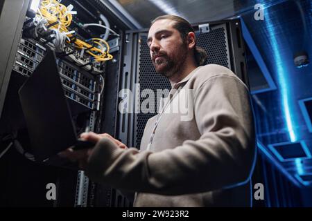 Engineer working on laptop near server room equipment Stock Photo